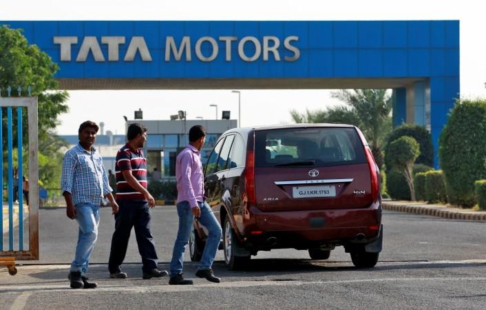 A vehicle drives past three men walking out of a Tata Motors car plant at Sanand in the western Indian state of Gujarat, India, October 27, 2016. tata motors, tata motors share price, tata motors share price, tata motors ceo, tata motors stock upgrade, jlr sales