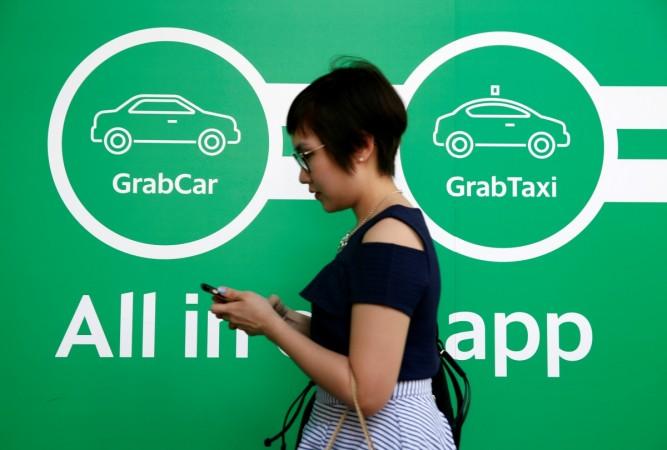 A woman passes a Grab signage at their office in Singapore September 23, 2016. grab, cab hailing app grab, grab rival uber, grab singapore, grab fund raising, grab investors, grab taxis