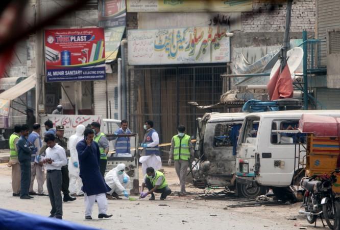 Forensic experts search for evidence at the site of an explosion, near vehicles taking part in census, in Lahore, Pakistan, April 5, 2017. Lahore Blast