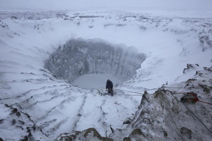 A member of an expedition group stands on the edge of a newly formed crater on the Yamal Peninsula, northern Siberia November 9, 2014. A group of scientists and discoverers in November went on an expedition initiated by the Russian Centre of Arctic Exploration to research the crater after pilots captured it on video in July 2014 which attracted the attention of world public. pingos, Arctic, craters, mystery, environment,