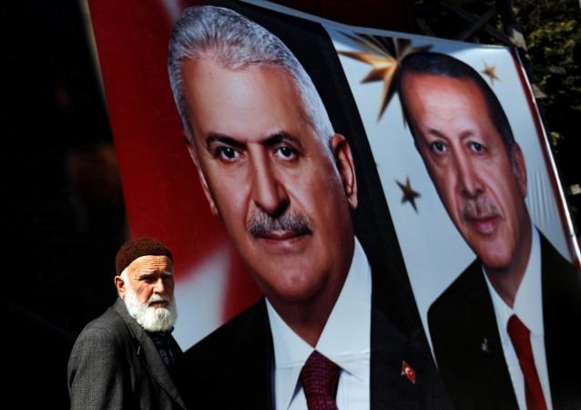 A man stands next to campaign posters of Prime Minister Binali Yildirim and President Tayyip Erdogan for the upcoming referendum Turkey referendum