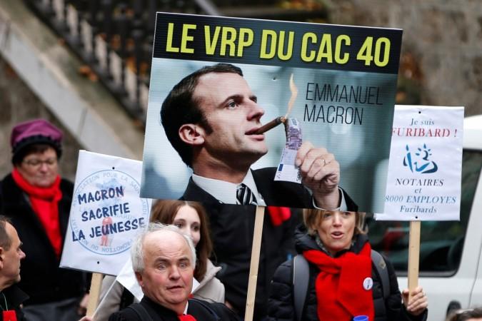 The placard shows French Economy Minister Emmanuel Macron with the slogan Macron
