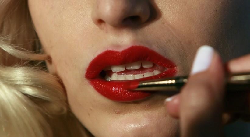 A makeup artist puts finishing touches on a model Red lips