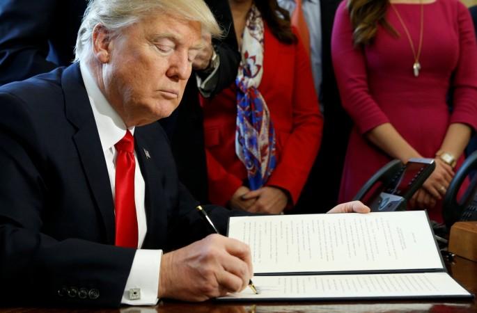U.S. President Donald Trump signs an executive order rolling back regulations from the 2010 Dodd-Frank law on Wall Street reform at the White House in Washington, February 3, 2017. donald trump tax plan, donald trump likely to cut corporate tax, trump administration tax rules, wall street, america inc us inc, american companies, taxation in america