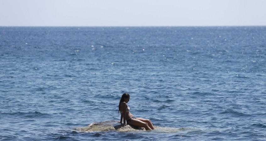 A tourist sunbathes on the Red Beach on the Greek island of Santorini, Greece, July 2, 2015 (representational image). makemytrip, makemytrip to raise $330 million, makemytrip share price, online travel portals, online travel booking