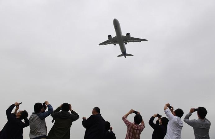 Spectators take photos as they watch the Comac C919, China's first large passenger jet, coming in for a landing on its maiden flight at Shanghai's Pudong airport on May 5, 2017. C919