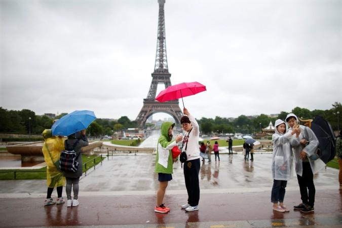 Tourists stroll on the Trocadero square, in front of the Eiffel Tower during a rainy day in Paris, France, May 30, 2016. french elections 2017, french polls 2017, Élysée palace, centrist emmanuel macron, far right marine le pen, french economy, india france bilateral trade, paris fashion, fashion shows in paris