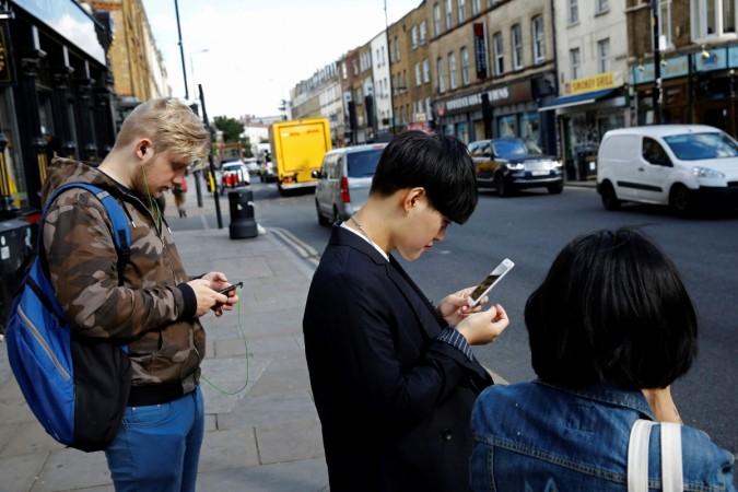 Pedestrians look at their mobile phones near Brick Lane in London, Britain. smartphone