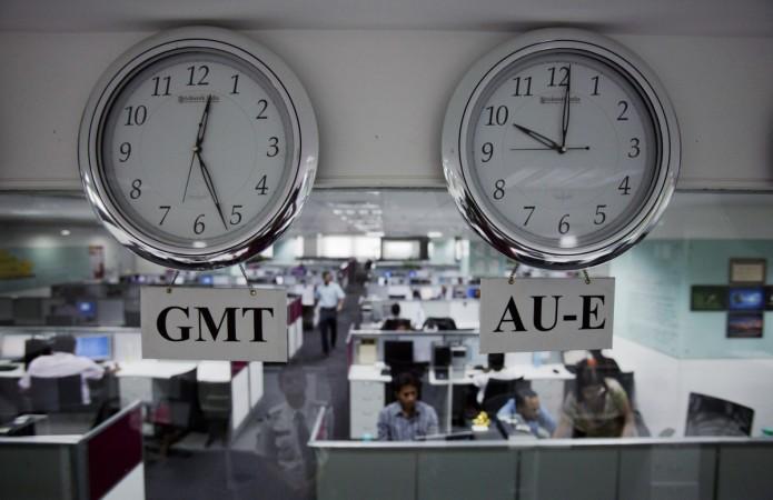 Workers are pictured beneath clocks displays time zones in various parts of the world at an outsourcing centre in Bangalore, February 29, 2012. layoffs, layoffs at it companies, it hiring, it recruitment, layoffs at wipro, layoffs at infosys, layoffs at capgemini, layoffs at cognizant, it stocks, tcs share price, h-1 b visa controversy