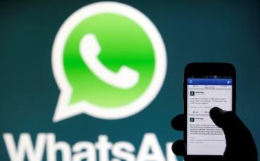 A WhatsApp logo is seen behind a phone