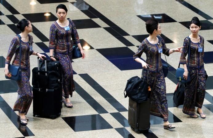 Singapore Airlines flight attendants walk to the departure gate at Changi Airport in Singapore May 11, 2016. cathay pacific, job cuts at cathay pacific, global aviation in turmoil, singapore airlines weak results, radical changes in singapore airlines
