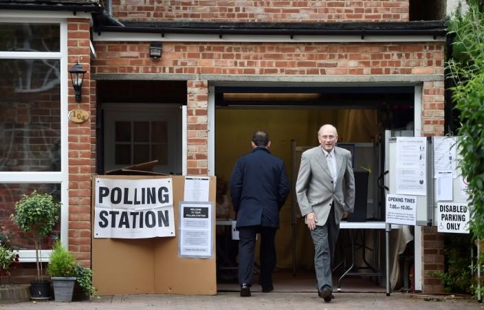 Voters leave and arrive at a garage which is being used as a polling station in Croydon, on general election day in south London, Britain UK polls