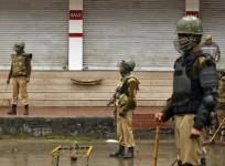 Indian policemen stand guard at a barricade setup during curfew of an area in Srinagar