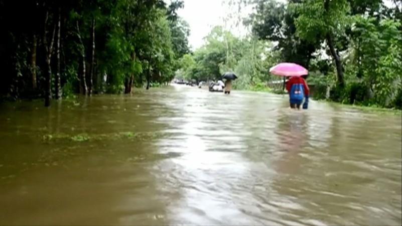 People walk in floodwaters following landslides triggered by heavy rain in Khagrachari, Bangladesh, in this still frame taken from video June 13, 2017. Bangladesh Landslide