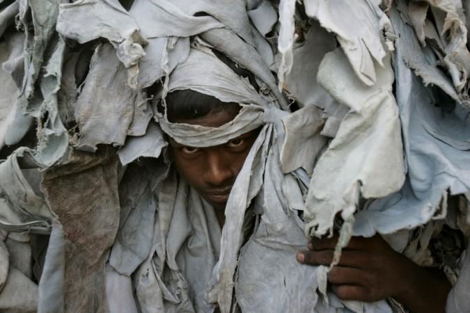 A labourer carries scrap leather from a traditional tannery in Kolkata May 24, 2008. India leather industry, tannery, cattle slaughter ban