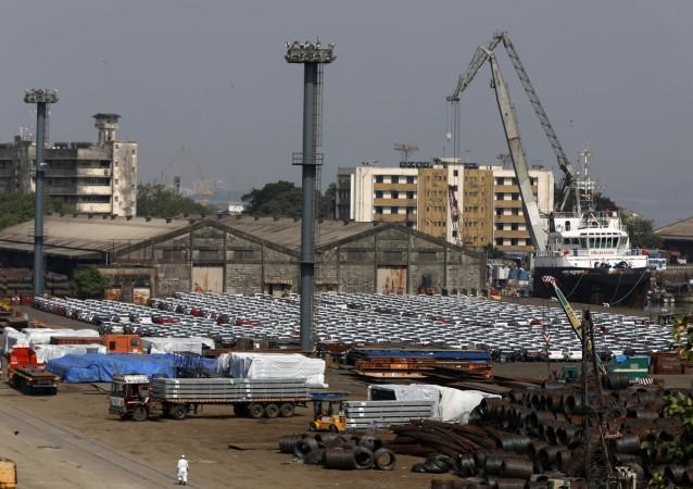A man walks past steel rims and parked cars at a dock yard at Mumbai Port Trust in Mumbai November 17, 2014. steel production in india, steel production japan, steel exports by india, steel imports by india, india news, steel, tata steel, factory, iip, indian economy, gdp