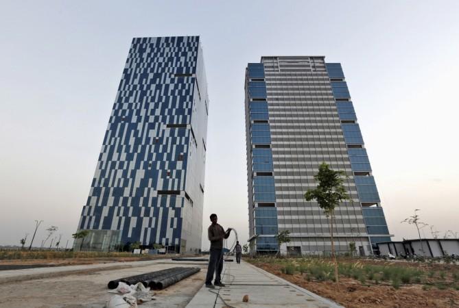 sA worker folds the cable of a welding machine in front of two office buildings at the Gujarat International Finance Tec-City (GIFT) at Gandhinagar in Gujarat in this file photo. India's push to accommodate a booming urban population and attract investment rests in large part with dozens of Smart city