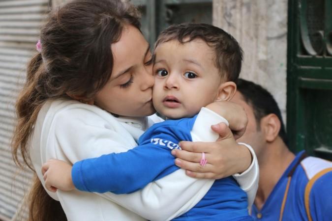 Syrian Bana al-Abed, who with the help of her mother had been posting heartrending tweets in English on life in the besieged eastern districts of Syria's Aleppo, is seen kissing her brother on October 10, 2016, in east Aleppo. Bana Alabed