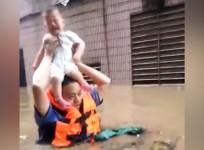 Police officer carries baby over head during deadly Chinese flood