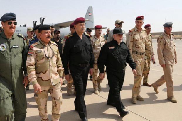 Iraqi Prime Minister Haider al-Abadi, dressed in a black military uniform and cap (R) Haider al-Abadi