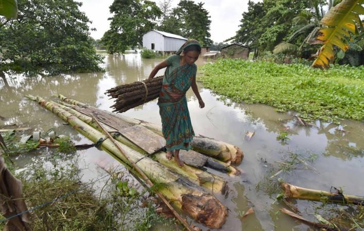 An Indian woman carries cow dung, which is used as fuel for fires, on a raft through floodwaters in Buraburi village in Morigoan district in the northeastern state of Assam. Assam Floods