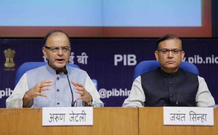 Finance Minister Arun Jaitley (left) gestures as Junior Finance Minister Jayant Sinha watches during a news conference in New Delhi, on August 14, 2015. India needs to minimise political interference in public sector banks, Finance Minister Jaitley said, as the government announced measures to improve the performance of state-run banks that are struggling with rising bad loans. REUTERS/Adnan Abidi Arun Jaitley