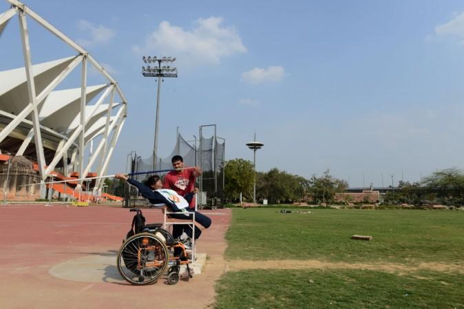 Disabled Indian sportswoman Deepa Malik is supervised by a coach while throwing a javelin during an athletics practice session at The Jawaharlal Nehru Stadium in New Delhi on March 5, 2014. Deepa Malik