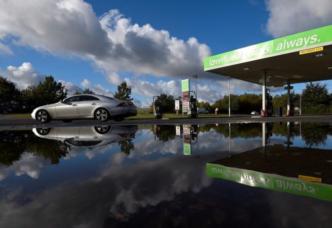 A customer drives away in a Mercedes-Benz after refuelling at an independent petrol station, with the slogan 'low fuel prices, always' across the forecourt roof, on an A road near Ely in Cambridgeshire, Britain. Britain cars, Britain petrol cars ban