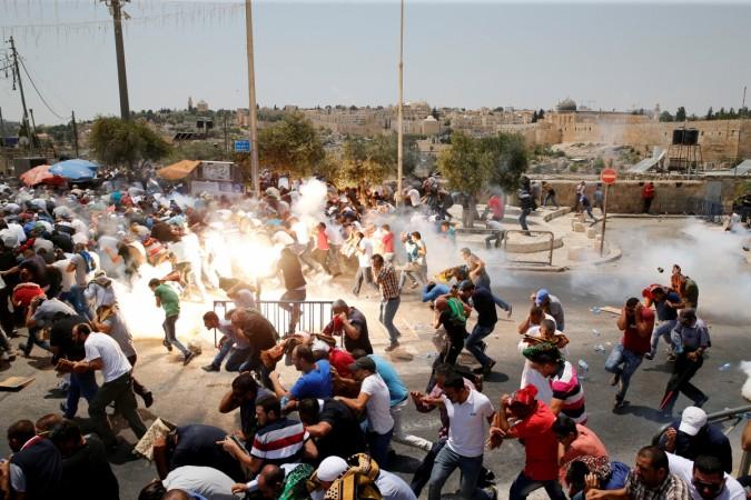 Palestinians react following tear gas that was shot by Israeli forces after Friday prayers on a street outside Jerusalem's Old city during a Israel