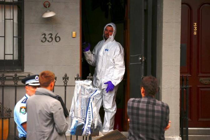 A police officer wearing protective gear talks to fellow officers as he stands in the doorway of a home after Australian counter-terrorism police arrested four people in raids late on Saturday across several Sydney suburbs in Australia, July 30, 2017. Australia