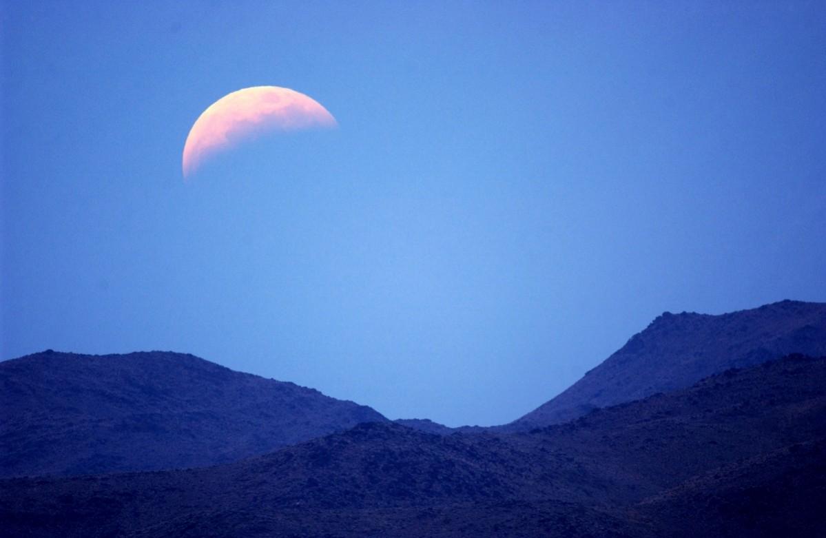The moon seen in total eclipse as it rises over the desert on May 15, 2003, in Joshua Tree National Park, California. Joshua Tree National Park