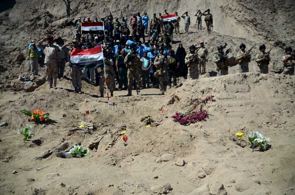 raqi soldiers salute as they stand next to a mass grave for Shi'ite soldiers from Camp Speicher who have been killed by Islamic State militants in the presidential compound of the former Iraqi president Saddam Hussein in Tikrit April 6, 2015. Iraqi forensic teams began on Monday excavating 12 suspected mass grave sites thought to hold the corpses of as many as 1,700 soldiers massacred last summer by Islamic State militants as they swept across northern Iraq. Camp Speicher massacre in 2014
