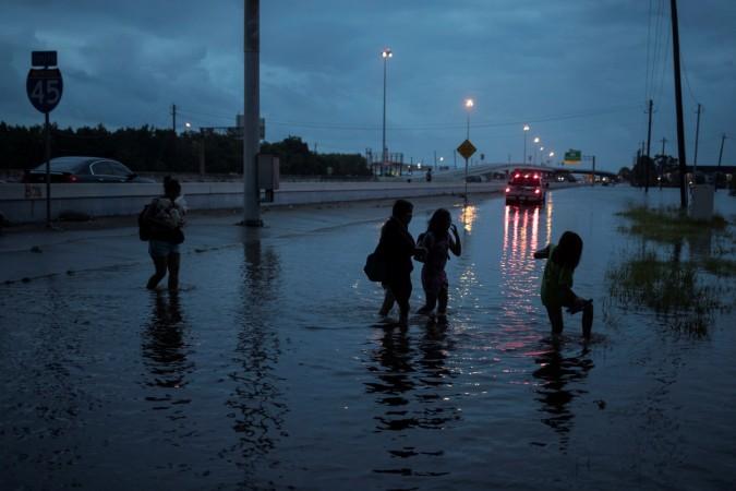 People walk through flood waters from Tropical Storm Harvey on the feeder road of Interstate 45 in Houston, Texas, U.S Tropical Storm Harvey