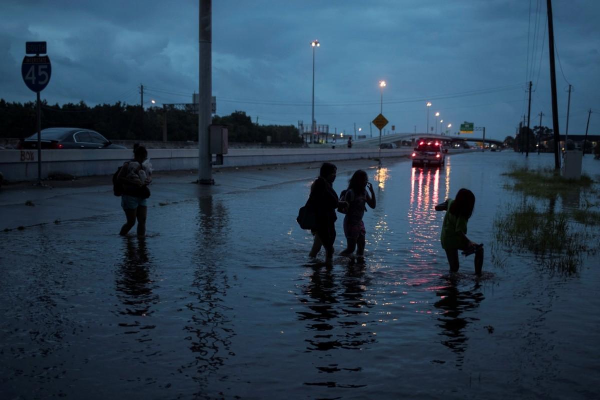 People walk through flood waters from Tropical Storm Harvey on the feeder road of Interstate 45 in Houston, Texas, U.S Tropical Storm Harvey