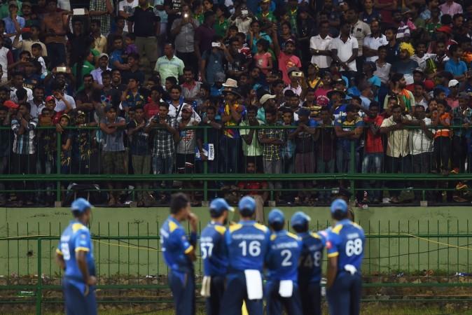 Sri Lanka's players wait for the game to resume after some spectators threw plastic bottles in the ground during the third one day international (ODI) cricket match between Sri Lanka and India at the Pallekele International Cricket Stadium in Pallekele on August 27, 2017 sri lanka cricket