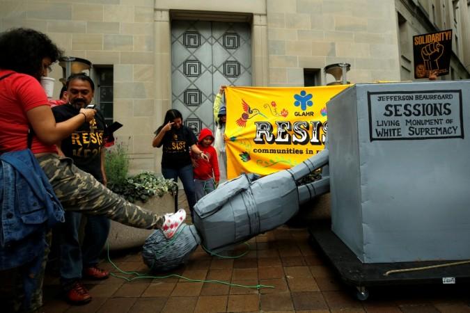 Immigration activists kick a statue of U.S. Attorney General Jeff Sessions after they pulled it down in front of the Justice Department in Washington DACA
