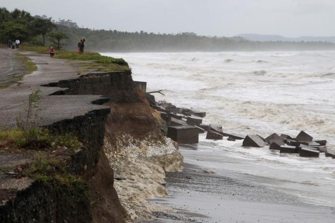 Locals stand next to a damaged road as Hurricane Irma moves off the northern coast of the Dominican Republic Irma