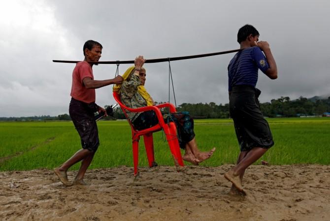 Rohingya refugee men carry an old woman as she is unable to walk after crossing the border, in Teknaf, Bangladesh. Rohingya refugee men carry an old woman as she is unable to walk after crossing the border, in Teknaf, Bangladesh.