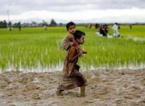 A Rohingya boy carries a child while walking in the mud after crossing the Bangladesh-Myanmar border in Teknaf, Bangladesh
