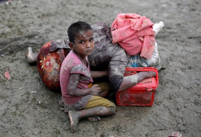 A Rohingya refugee girl sits next to her mother who rests after crossing the Bangladesh-Myanmar border, in Teknaf, Bangladesh. A Rohingya refugee girl sits next to her mother who rests after crossing the Bangladesh-Myanmar border, in Teknaf, Bangladesh.