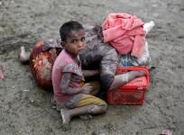 A Rohingya refugee girl sits next to her mother who rests after crossing the Bangladesh-Myanmar border, in Teknaf, Bangladesh.