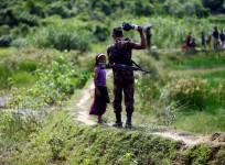 A member of Border Guard Bangladesh (BGB) tells a Rohingya girl not to come on Bangladesh side, in Cox's Bazar, Bangladesh