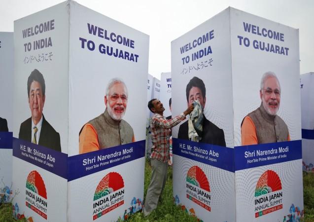 A worker cleans a hoarding featuring India's Prime Minister Narendra Modi and his Japanese counterpart Shinzo Abe ahead of Abe's visit, in Ahmedabad, India, September 10, 2017. Shinzo Abe Modi Gujarat