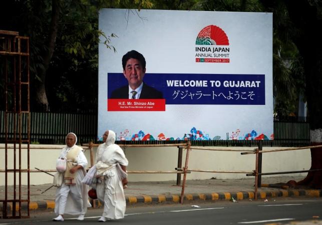 Women walk past a billboard featuring Japanese Prime Minister Shinzo Abe ahead of Abe's visit, in Ahmedabad, India, September 11, 2017. Shizno Abe Modi