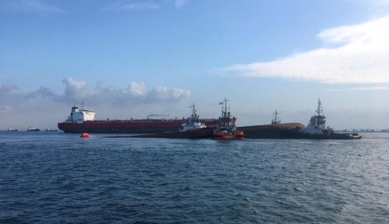 Four tug boats move a partially submerged Dominican-registered dredger safely into an area after a collision with an Indonesian-registered tanker Singapore ship crash