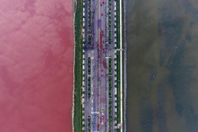 A salt lake which is separated by a road, shows parts of it in different colours due to algae, in Yuncheng, Shanxi Province, China, September 25, 2016. Dead Sea in China