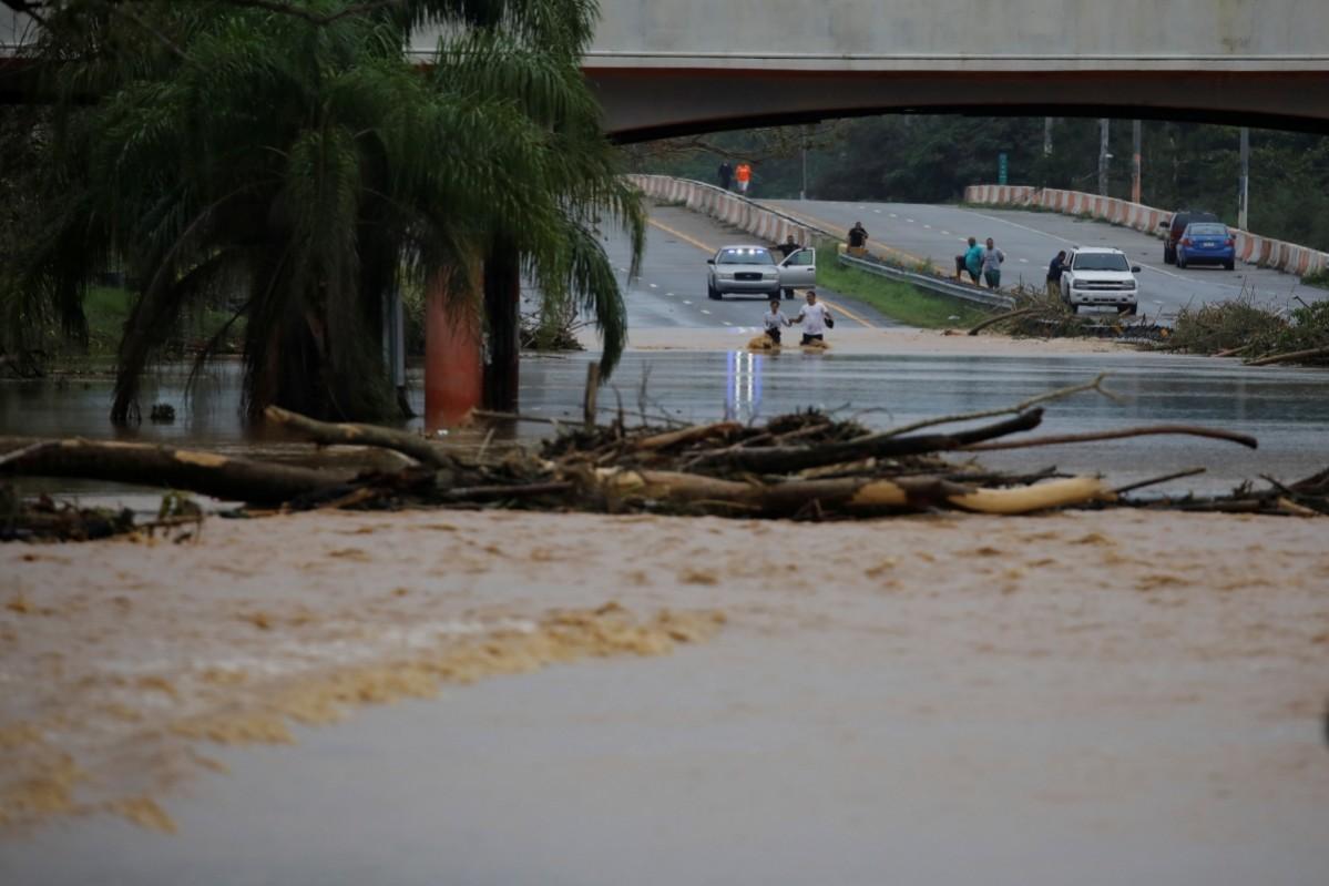 People wade through a flooded expressway after the area was hit by Hurricane Maria in Yauco, Puerto Rico Hurricane Maria