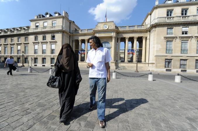 Hind, a Niqab veiled woman (L) and real estate magnate Rachid Nekkaz (R) who supports Muslim women fined for wearing the burka or niqab on the street walk in front of the French National Assembly during a symbolic protest against France's ban on wearing full-face niqab veils in public, on April 20, 2011 in Paris. French officials estimate that only around 2,000 women, from a total Muslim population estimated at between four and six million, wear niqabs, which are traditional in parts of Arabia and South Asia Rachid Nekkaz