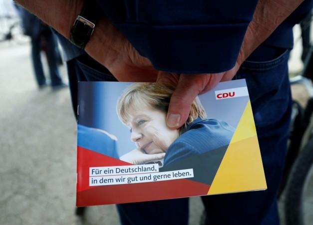 A man holds CDU flyer as German Chancellor Angela Merkel campaigns in Heppenheim, Germany, September 22, 2017. Germany polls