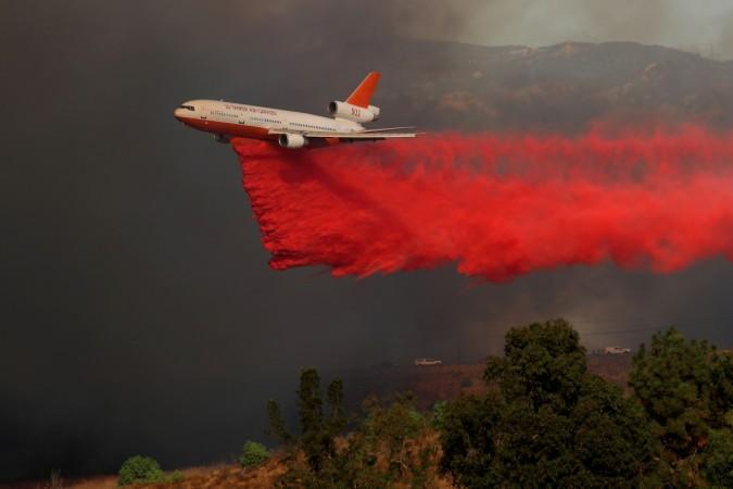 A DC-10 aircraft drops fire retardant on a wind driven wildfire in Orange. California